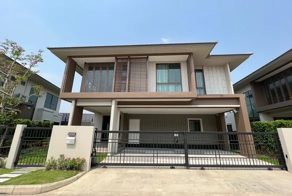 Modern two-story house with a flat roof, large windows, and a gated driveway.