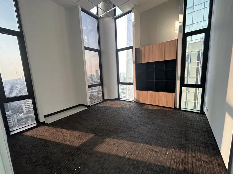 ห้องทำงานว่างเปล่าที่มีหน้าต่างสูงจากพื้นจรดเพดานและชั้นวางของไม้บิวท์อิน มองเห็นวิว