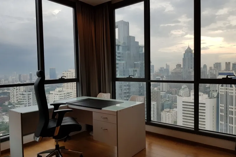 article image - Office room with a desk and chair against floor-to-ceiling windows overlooking a city skyline at dusk. Office room with a desk and chair against floor-to-ceiling windows overlooking a city skyline at dusk.
