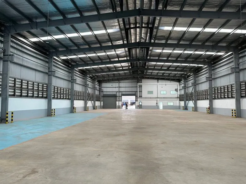 Large empty warehouse interior with high ceilings, metal beams, and ample space.