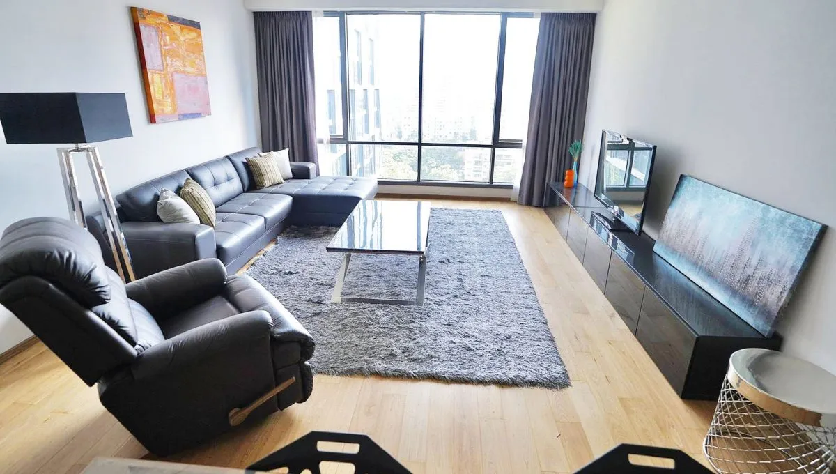 article image - Modern living room with a black leather sectional sofa, a recliner, a glass coffee table, a large window, wall art, and a flat-screen TV on a sleek media unit. Modern living room with a black leather sectional sofa, a recliner, a glass coffee table, a large window, wall art, and a flat-screen TV on a sleek media unit.