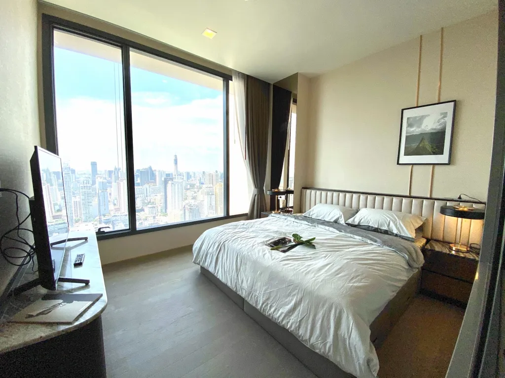 article image - Modern bedroom with a large window showcasing a city skyline, featuring a comfortable bed, a wall-mounted TV, and contemporary decor. Modern bedroom with a large window showcasing a city skyline, featuring a comfortable bed, a wall-mounted TV, and contemporary decor.