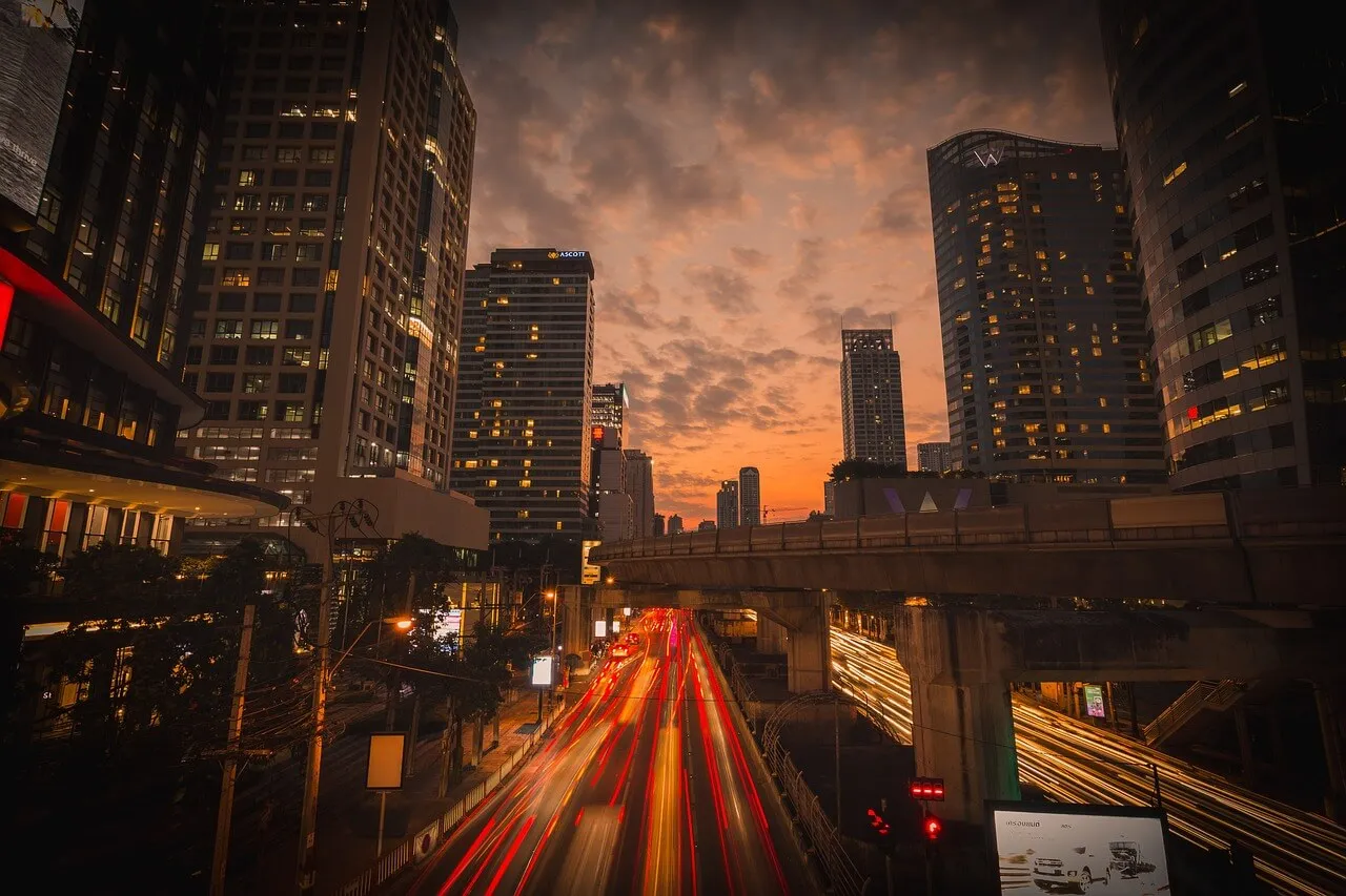 黄昏时分的城市景观，摩天大楼林立，繁忙的道路上车辆的灯光轨迹模糊不清。