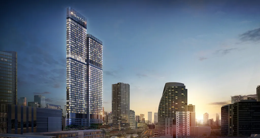 City skyline at sunset featuring the Ashton high-rise building with lights on.