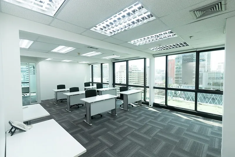 พื้นที่สำนักงานทันสมัย ​​พร้อมโต๊ะ เก้าอี้ และหน้าต่างบานใหญ่ที่มองเห็นทิวทัศน์เมือง