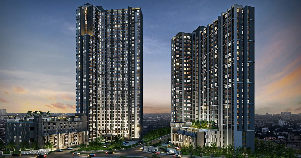 Two modern high-rise buildings with illuminated windows against a twilight sky, surrounded by greenery and cityscape.