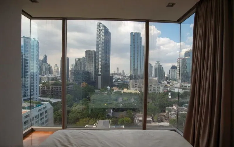ภาพวิวเส้นขอบฟ้าของเมืองที่มีตึกระฟ้าทันสมัย ​​มองเห็นได้จากหน้าต่างบานใหญ่ในห้องนอน