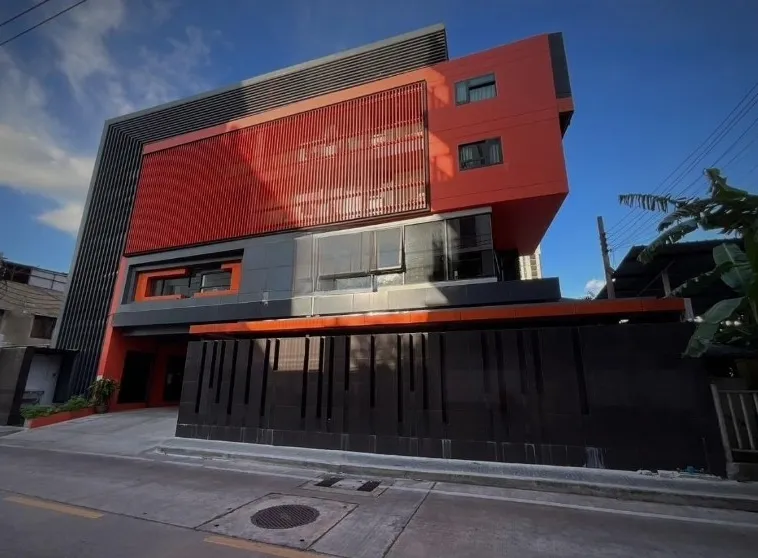 现代建筑，红黑相间的外墙，垂直的板条和几何设计元素，在湛蓝的天空下熠熠生辉。