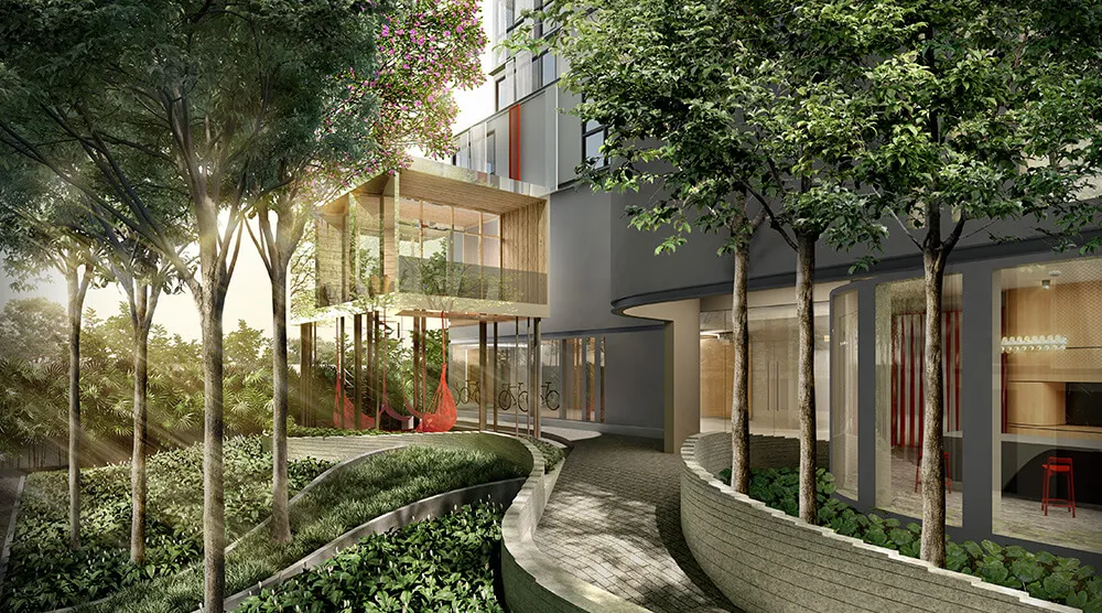 Modern building exterior with glass facade, elevated patio, and surrounding greenery. Pathway curves beside trees and landscaped plants under soft sunlight.