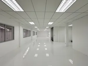 A large, empty, white office space with tiled flooring and fluorescent lights on the ceiling.