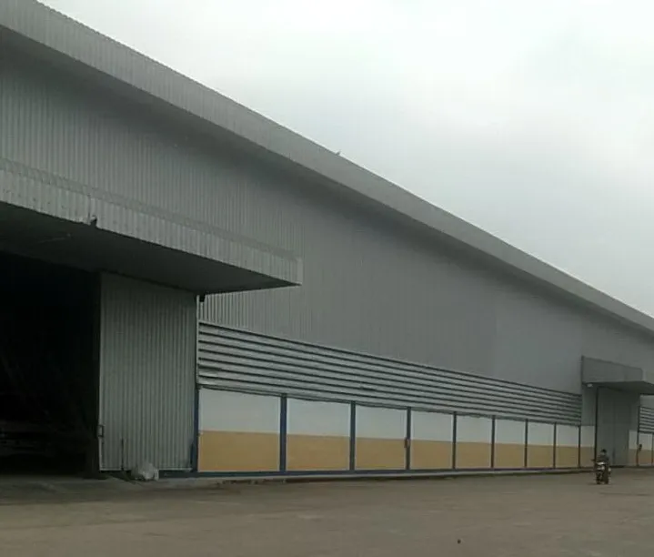 Large industrial warehouse with a corrugated metal exterior and open loading dock.