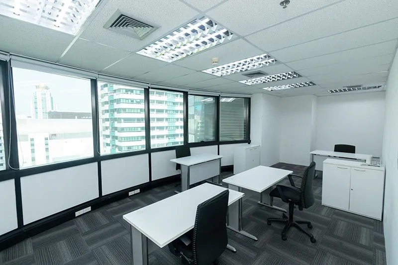 article image - A modern office space with white desks, black chairs, gray carpet, and large windows showing city buildings. A modern office space with white desks, black chairs, gray carpet, and large windows showing city buildings.