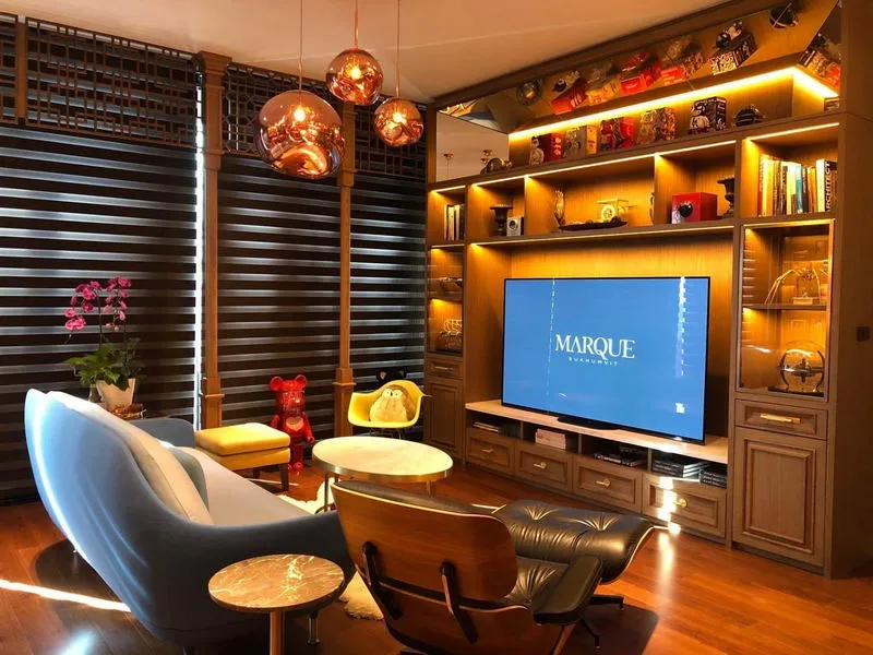 Modern living room with stylish furniture, TV, decorative shelving, and warm lighting.