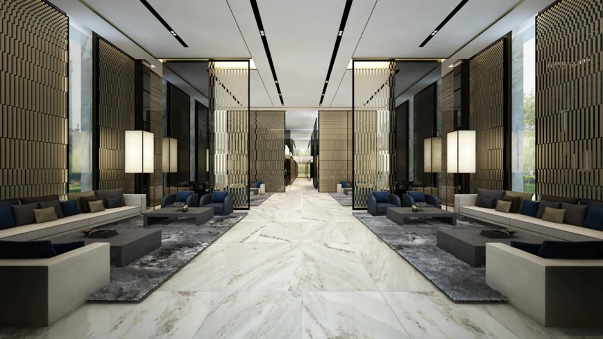 Luxurious hotel lobby with modern seating, marble floors, and tall decorative walls creating a spacious, elegant ambiance.