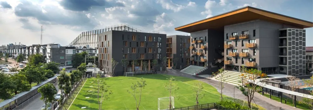 บริเวณโรงเรียนที่ทันสมัย ​​ประกอบด้วยอาคารสามชั้น สนามกีฬา และทิวทัศน์เมืองภายใต้ท้อง