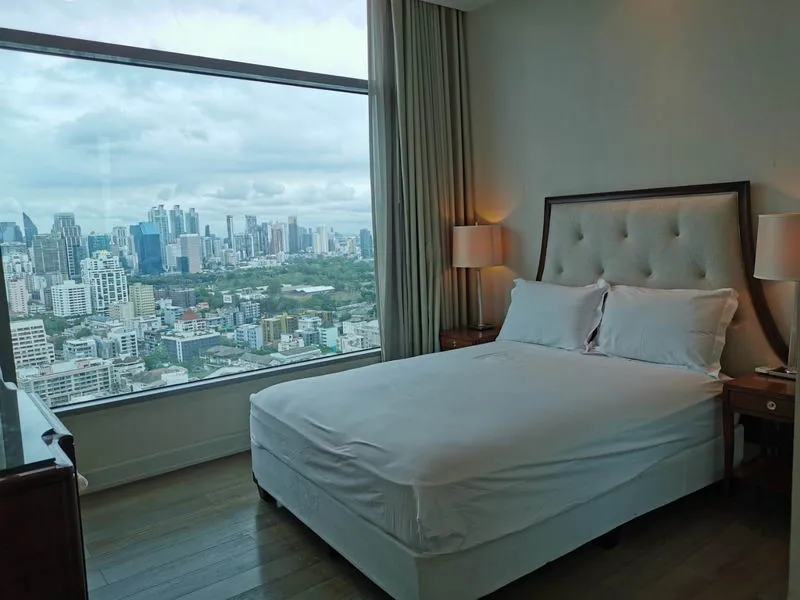Modern bedroom with large window and city skyline view.