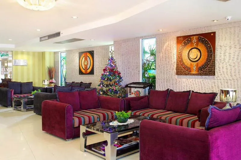 Lobby with purple sofas, colorful cushions, a glass coffee table, abstract art on the walls, and a decorated Christmas tree in the corner.