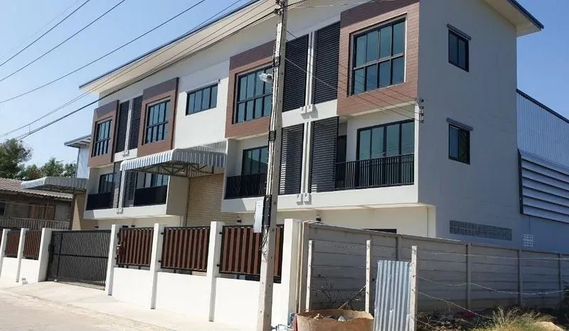 现代化的两层建筑，设有大窗户和阳台，入口处有大门，周围环绕着混凝土围墙。