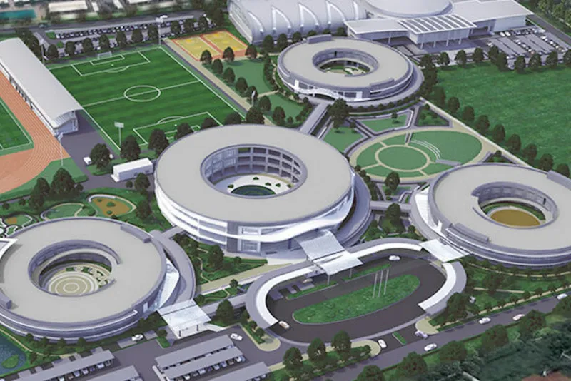 Aerial view of a modern campus with circular buildings, sports fields, and landscaped gardens.