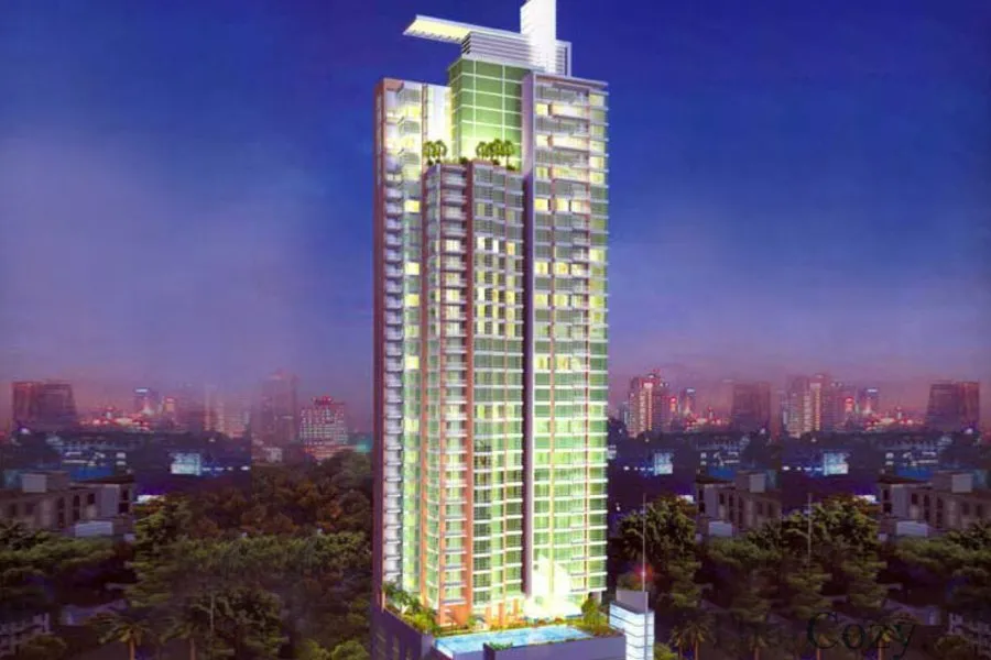 A tall illuminated skyscraper against a city skyline at dusk.