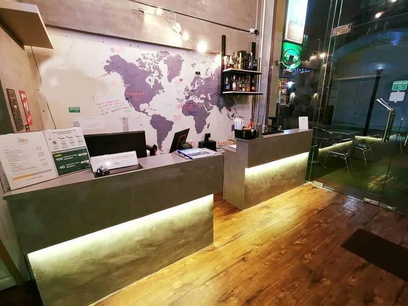 เคาน์เตอร์ต้อนรับของโรงแรม มีภาพวาดแผนที่โลกอยู่ด้านหลัง ดีไซน์ทันสมัย ​​พื้นไม้ และเค