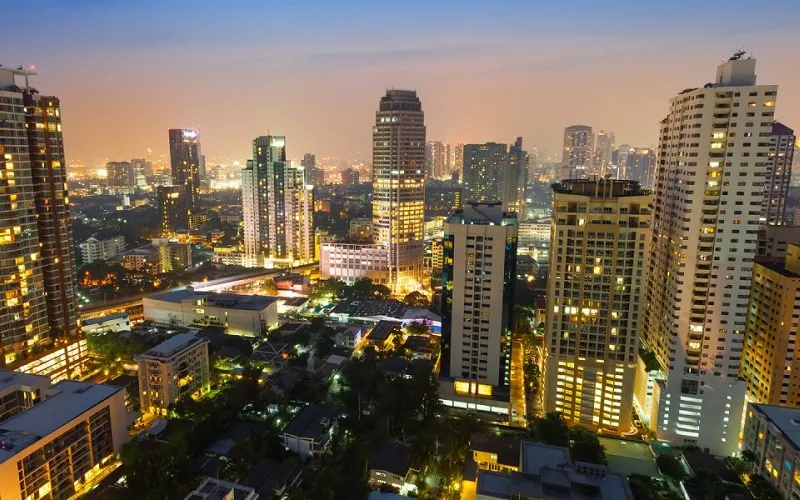 黄昏时分的城市鸟瞰图，高耸入云的摩天大楼灯火辉煌，背景是绚丽多彩的天空。