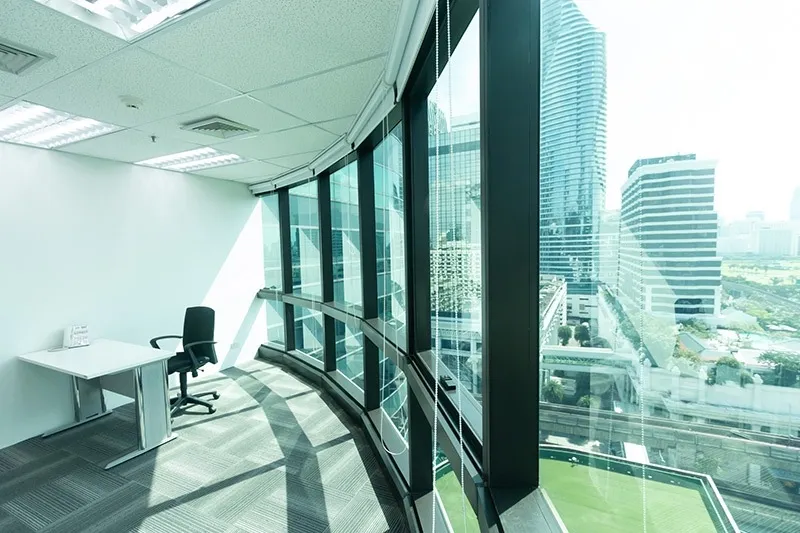 article image - Modern office with large glass windows offering a panoramic city view, featuring a single desk and chair. Modern office with large glass windows offering a panoramic city view, featuring a single desk and chair.