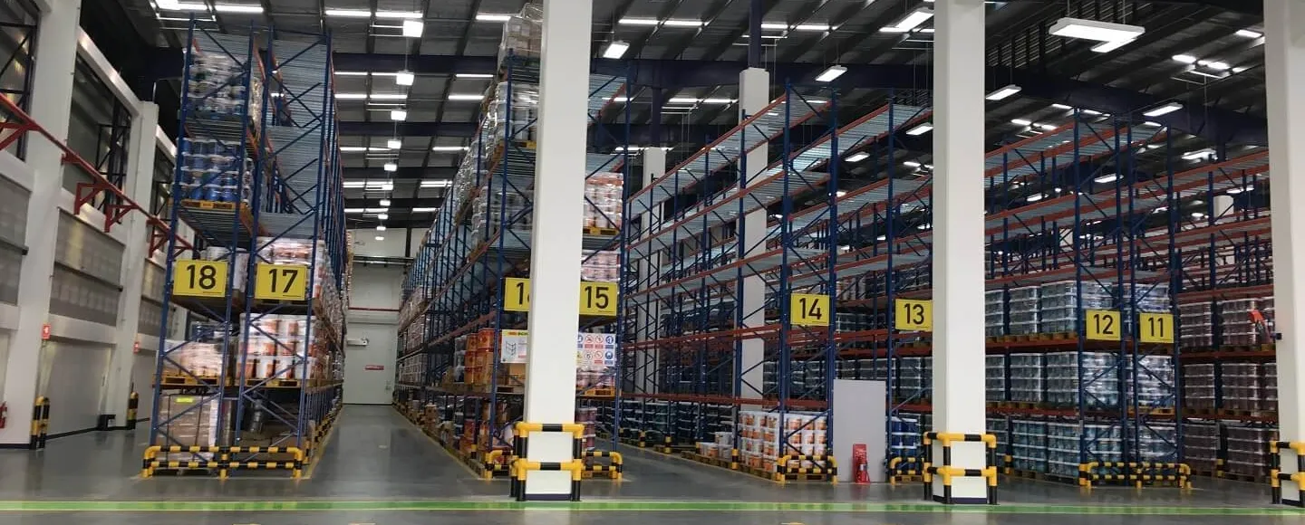 ภายในโกดังมีชั้นวางสูง หมายเลข 18 ถึง 11 เรียงกัน บรรจุสินค้าหลากหลายชนิด พื้นที่สว่างไสว แ