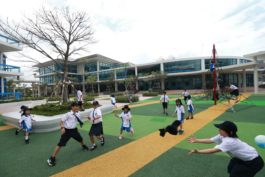 article image - Children playing in a school courtyard with modern buildings, climbing structure, and trees. Kids are engaged in various activities, enjoying the open space under a partly cloudy sky. Children playing in a school courtyard with modern buildings, climbing structure, and trees. Kids are engaged in various activities, enjoying the open space under a partly cloudy sky.