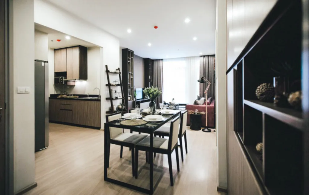 Modern open-concept living space with a dining table set, adjacent kitchen, and cozy seating area near a window.