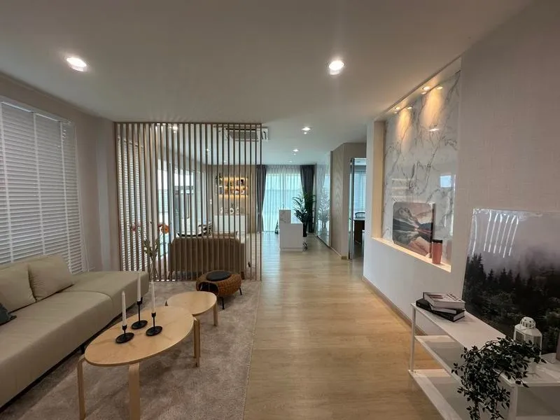 现代客厅，配有米色沙发、木质咖啡桌、装饰木条、大理石装饰墙，以及从大窗户透进来的自然光。