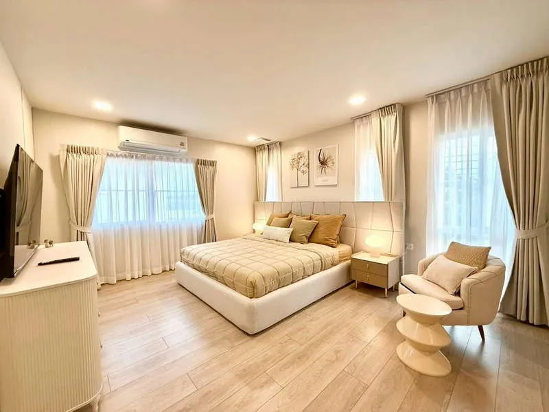 article image - Modern bedroom with a king-size bed, light wood flooring, armchair, and neutral decor. Large windows with sheer curtains allow natural light to fill the space. Modern bedroom with a king-size bed, light wood flooring, armchair, and neutral decor. Large windows with sheer curtains allow natural light to fill the space.