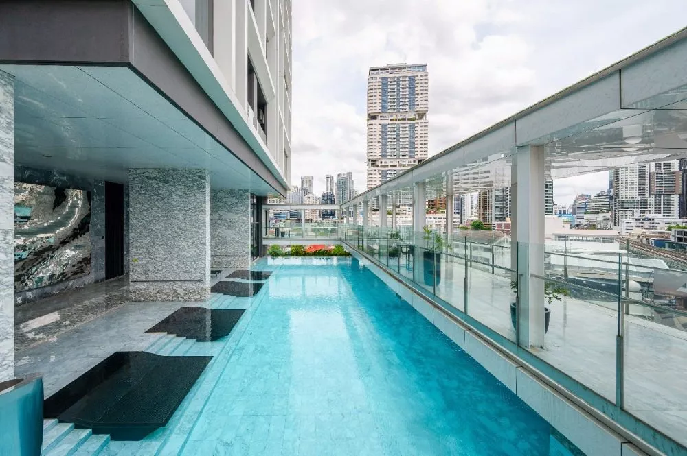 page image - Rooftop pool with a cityscape view, featuring a modern building and glass railing, under a partly cloudy sky. Rooftop pool with a cityscape view, featuring a modern building and glass railing, under a partly cloudy sky.