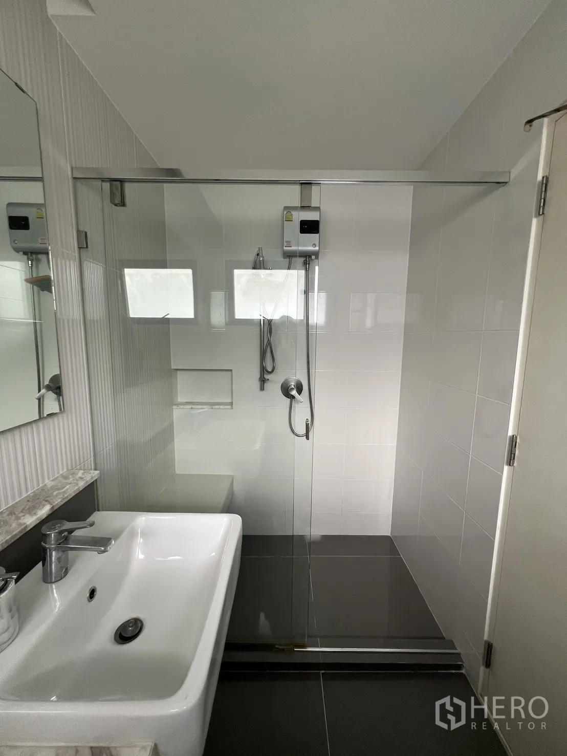 Detached House for rent in Bang Phli, Samut Prakan - Bathroom with glass shower enclosure, white basin and tiled walls.