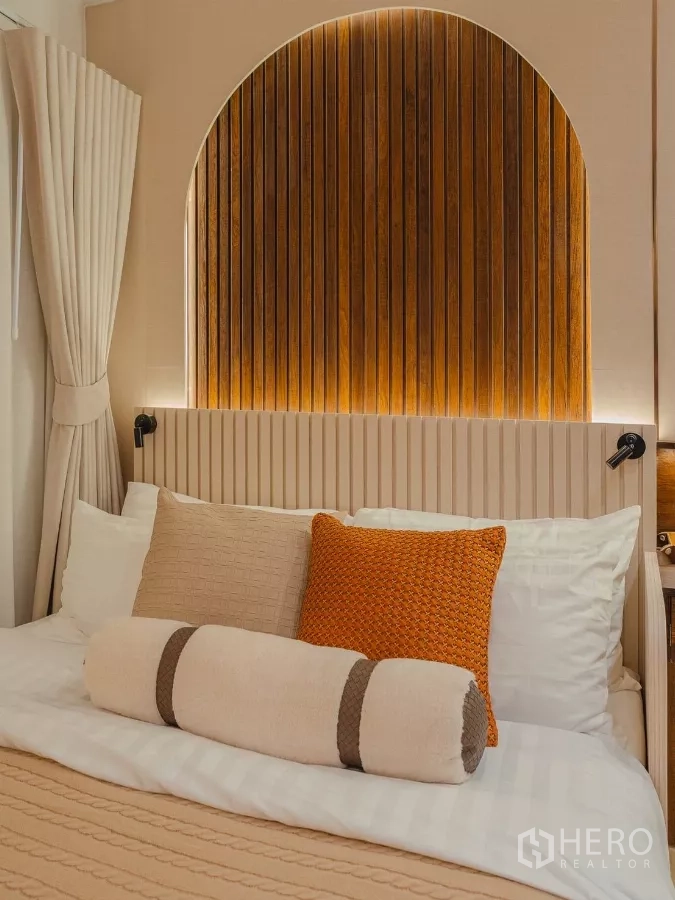 Condominium for rent in Yan Nawa, Bangkok - Detail of bed with layered pillows and an arched slatted wood headboard.