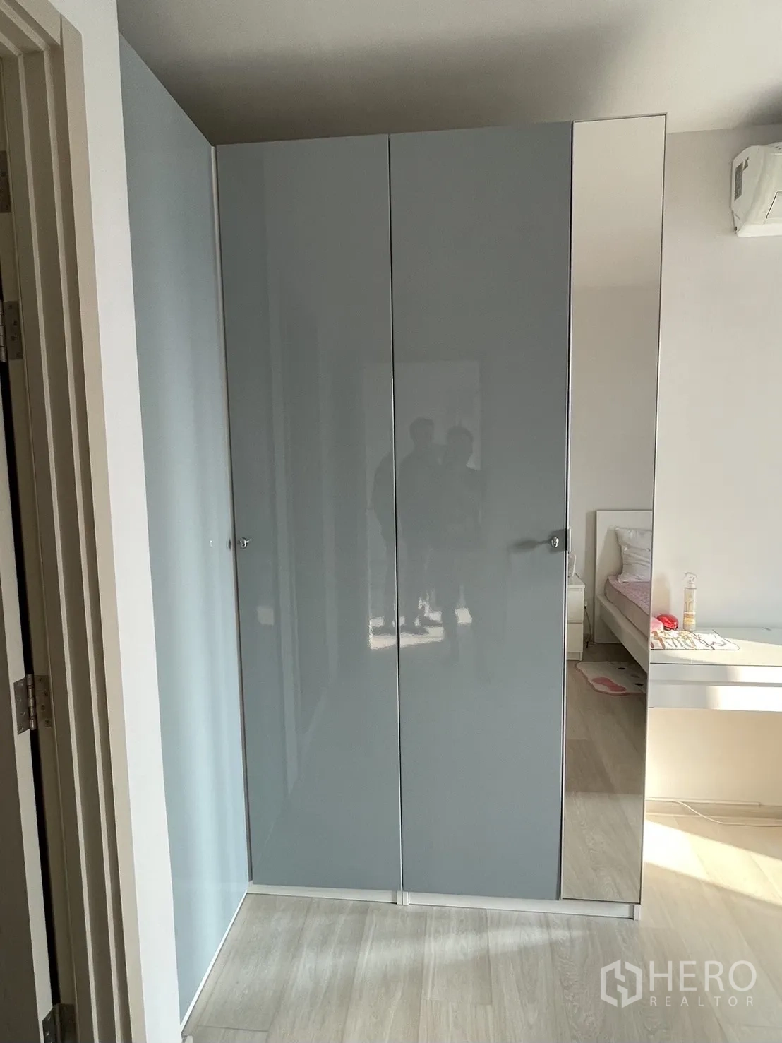 Condominium for rent in Pathum Wan, Bangkok - Glossy gray built-in wardrobe along a light wood hallway beside a bedroom entrance.