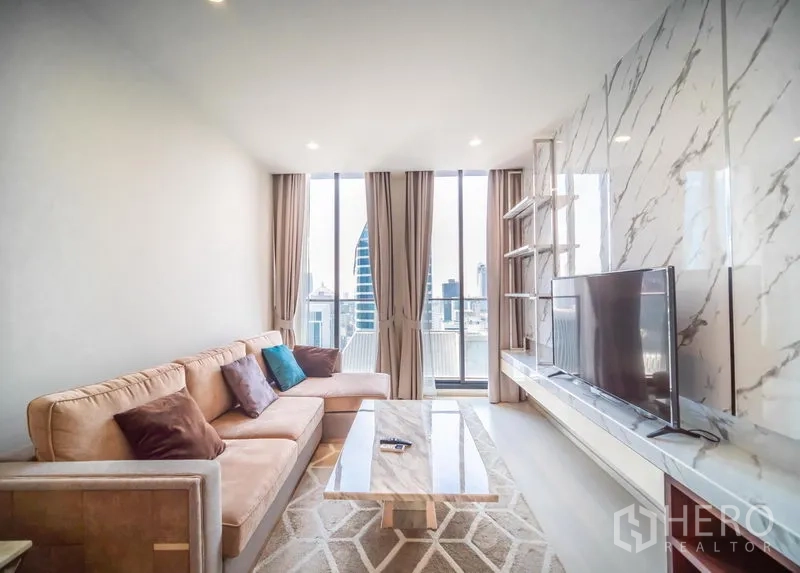 Condominium for rent in Pathum Wan, Bangkok - Living area with L-shaped sofa, marble coffee table and panoramic skyline through tall windows.