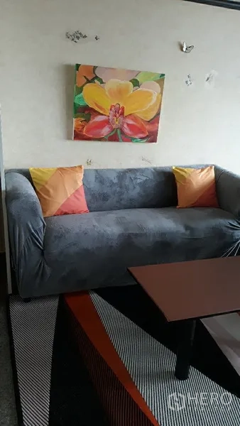 公寓 出售在Watthana, Bangkok - 客厅沙发搭配彩色抱枕，墙上大型花卉装饰画。