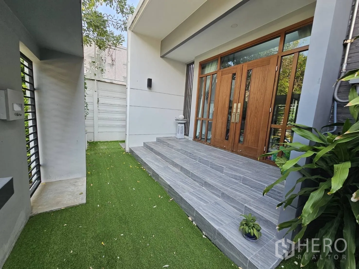 Detached House for rent in Wang Thonglang, Bangkok - Front steps leading to large wooden double doors beside a small lawn and greenery.