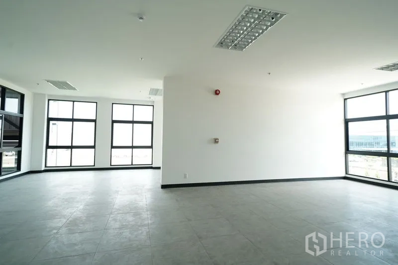 Warehouse for rent in Khlong Luang, Pathum Thani - Bright two-story office space with large windows, tiled flooring, and recessed lighting.