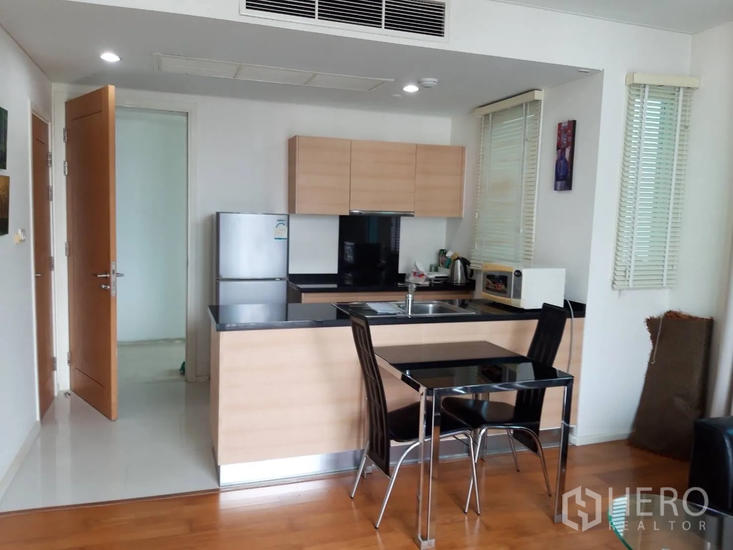 Condominium for rent in Watthana, Bangkok - Kitchen with black stone counters and a two-seat dining table.