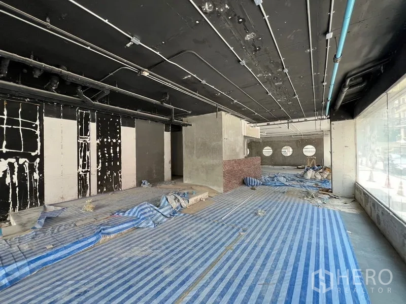 零售空间 出租在Watthana, Bangkok - 纵深商铺，黑色天花、玻璃门面与半高砖墙。