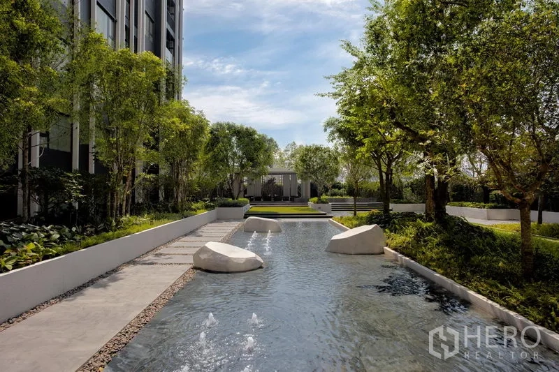 Condominium for rent in Pathum Wan, Bangkok - Serene water feature with stepping stones and small fountains amid lush trees and walkways.