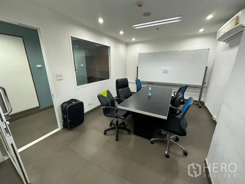 Office Space for rent or sale - Small meeting room with whiteboard, rectangular table and swivel chairs.