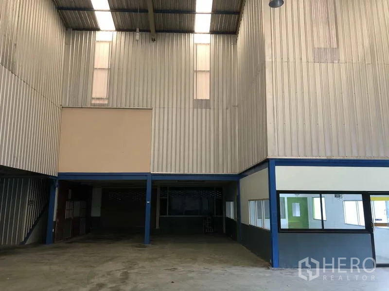 Warehouse for rent in Bang Phli, Samut Prakan - Back area featuring mezzanine-style storage bays under a tall ceiling.
