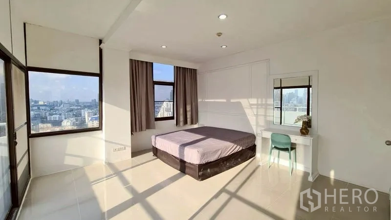 Condominium for rent in Watthana, Bangkok - Bedroom with large windows, bed, and a small dressing desk.