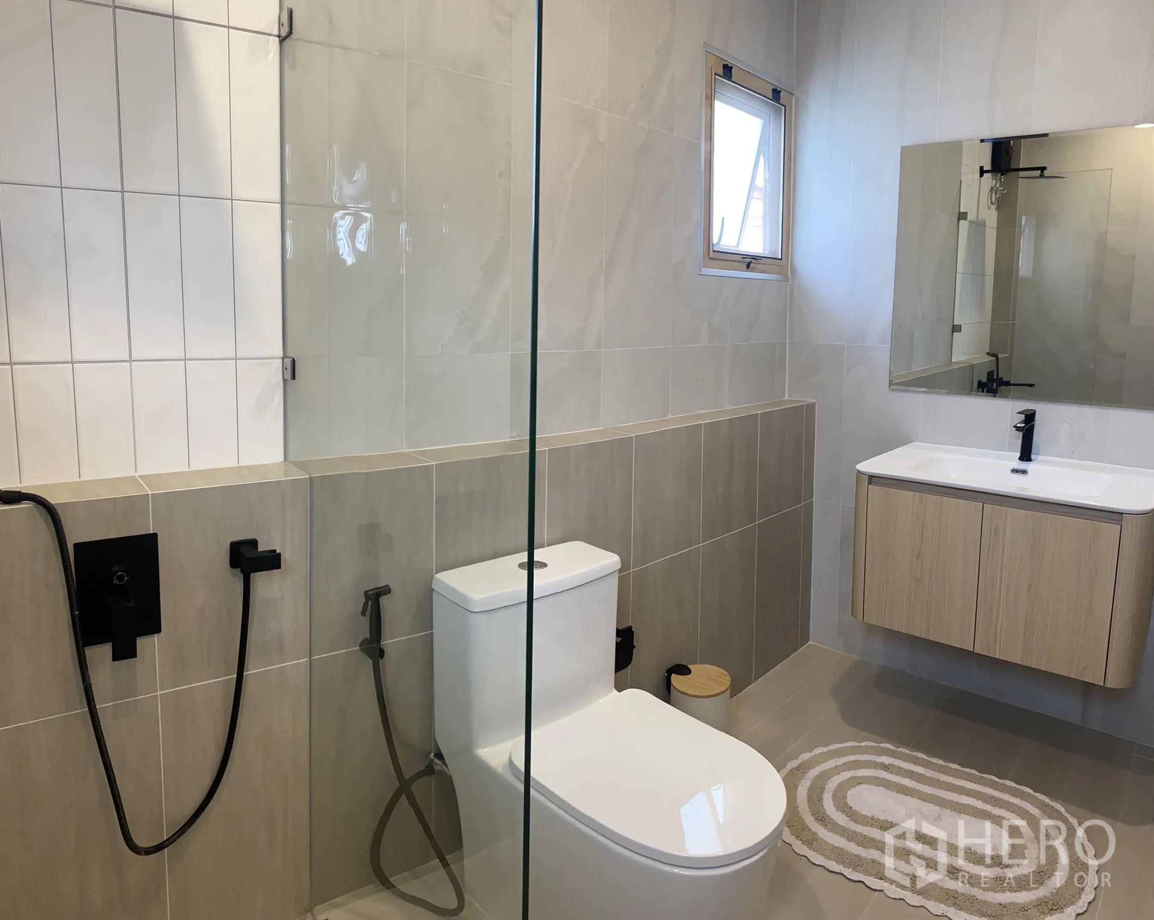 独立式住宅 出售在Suan Luang, Bangkok - 卫浴带玻璃隔断淋浴、悬空浴柜与黑色龙头。