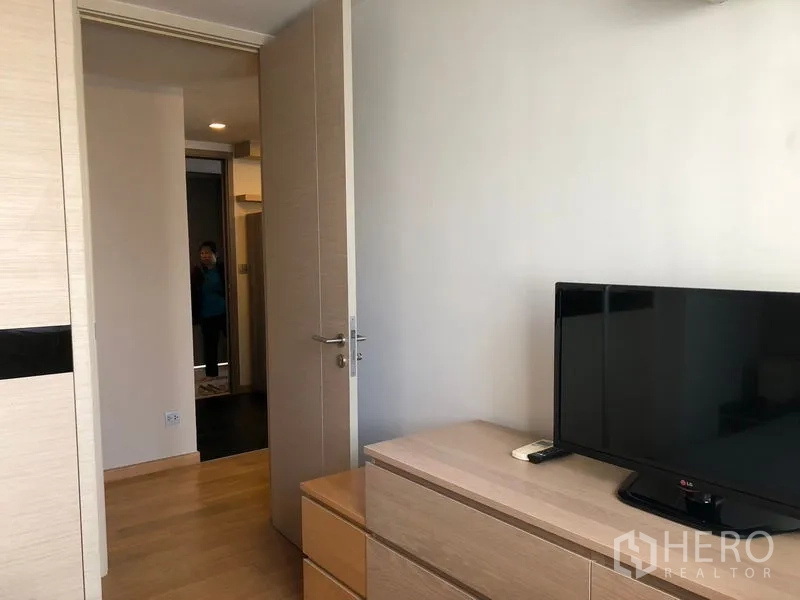 คอนโด ให้เช่าในWatthana, Bangkok - มุมห้องนอนพร้อมทีวีจอแบนบนตู้เตี้ยและประตูเชื่อมสู่โถงทางเดิน