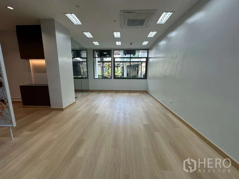 Office Space for rent - Open office room facing wide windows overlooking courtyard greenery.