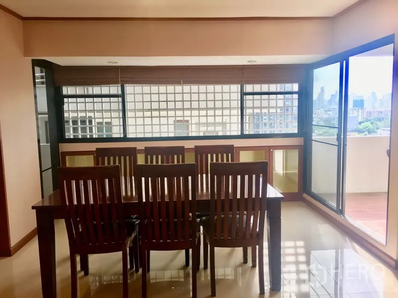 Condominium for rent in Watthana, Bangkok - Bright dining area with wooden table for six, floor-to-ceiling windows and a balcony city view in an Ekkamai condo.